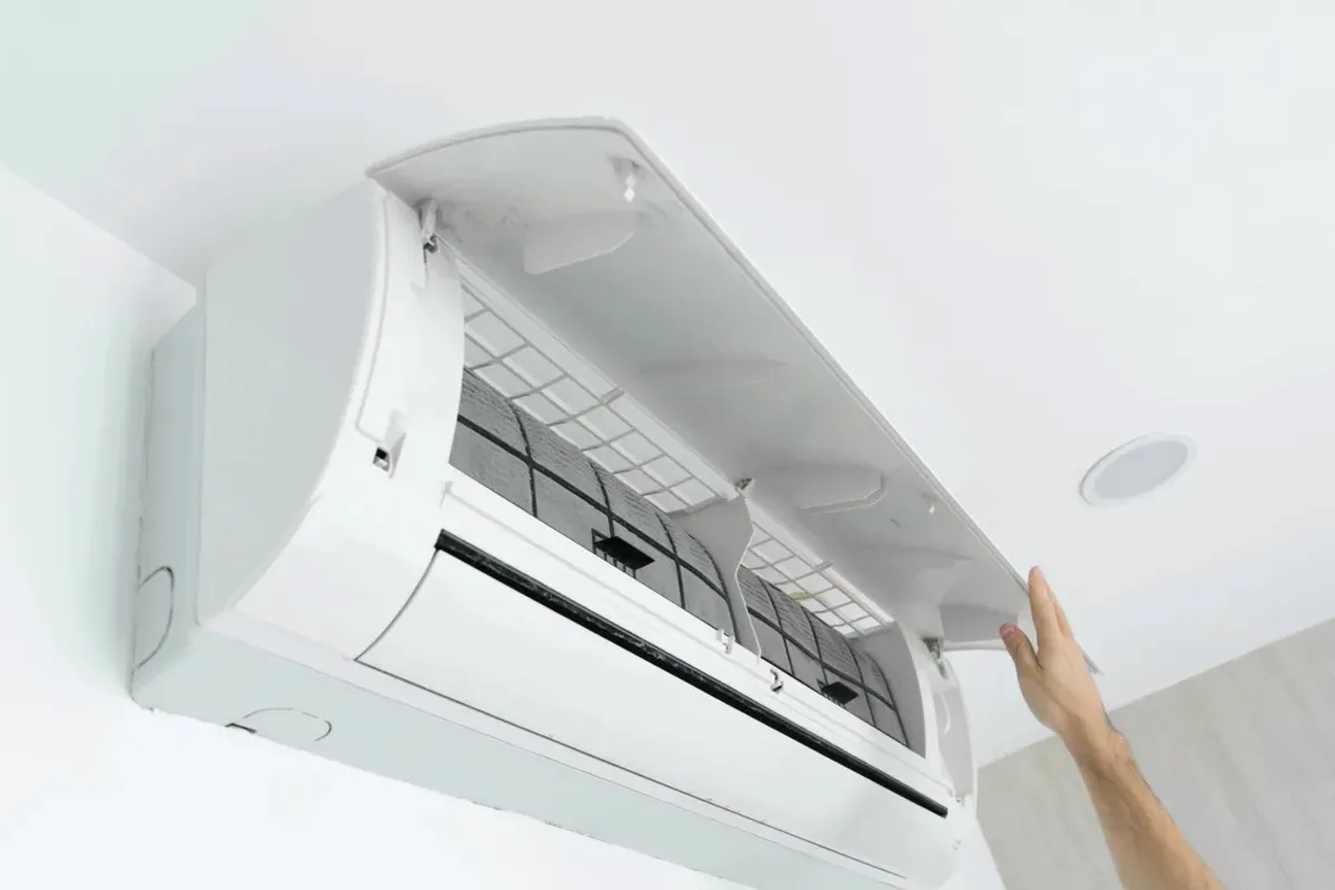 Hand opening the cover of a wall-mounted ductless air conditioner